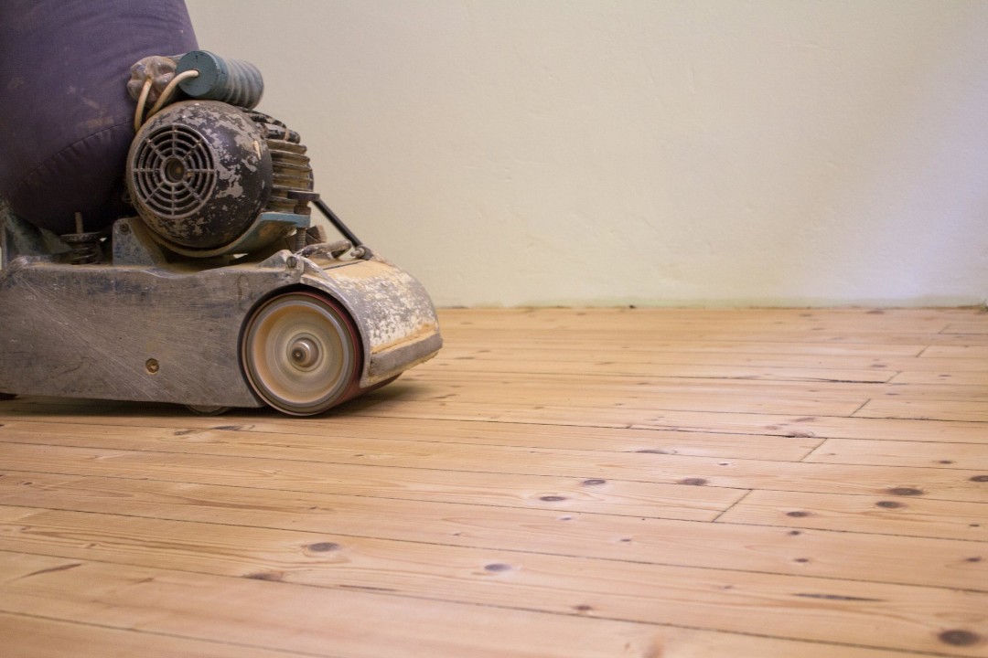 Sanding as part of the process of refinishing a hardwood floor.