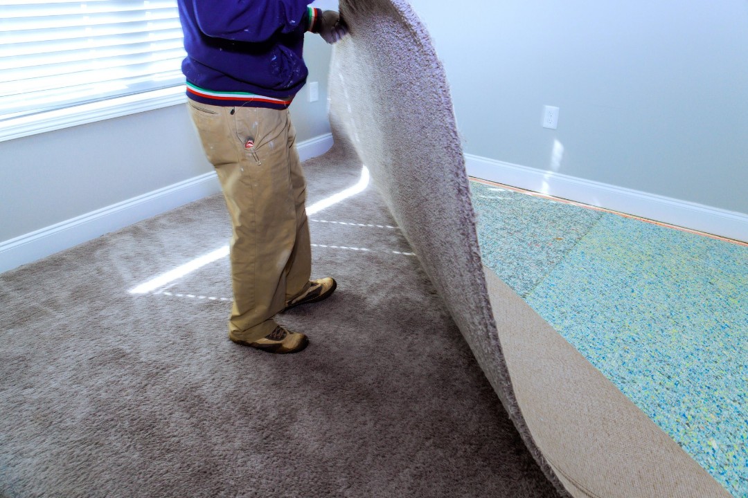 Worker removing carpet to remove padding